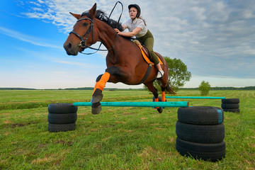 Pretty young girl jockey and her horse jumper