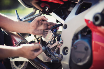 Close up Young White Guy Fixing Some Parts of his Blue Motorbike Using his Bare Hands.