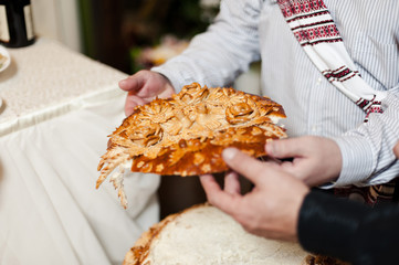 Closeup photo of bride and groom breaking traditional loaf