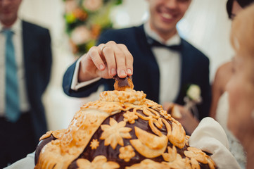 Closeup photo of bride and groom breaking traditional loaf