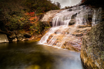 beautiful waterfall flowing gently over reddish rocks in the Appalachians of North Carolina during fall