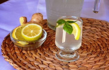 Fresh cold lemonade with a piece of lemon, ice and ginger on a glass.