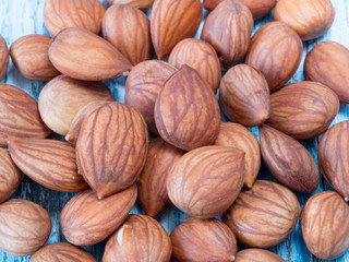 Heap of brown apricot kernels on wooden background close up