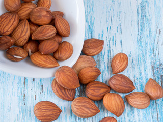 Heap of brown apricot kernels on wooden background close up