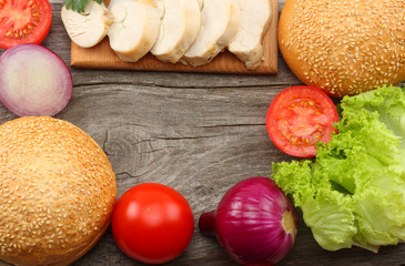 Hamburger Building Kit. round sandwich bun with, tomato, red onion, green lettuce, grilled chicken fillet on old wooden background. Top view with copy space.