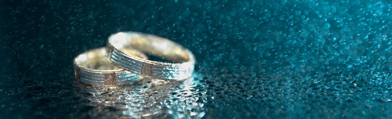 Wedding rings with rain drops closeup, soft focus, border design panoramic banner 