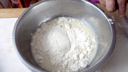 Adding flour to the base for the dough in a metal bowl