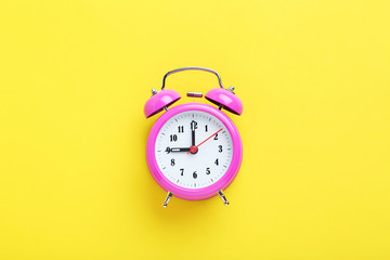 Pink alarm clock on the yellow background