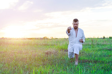 Martial art of karate, a man in a kimono trains in the open air, free space. A man is training at sunrise