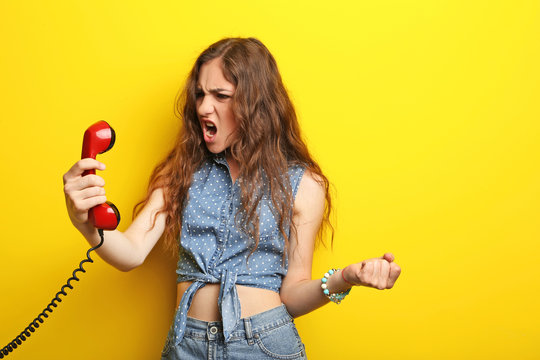 Portrait Of Young Woman With Red Phone On Yellow Background