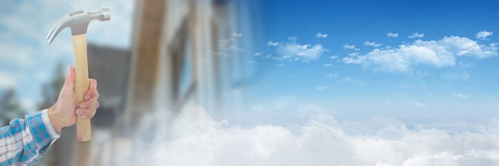 Hand with hammer on building site with sky transition effect