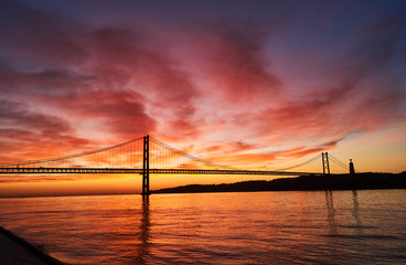 Fototapeta na wymiar clouds on fire on a sunrise in Lisbon, Portugal, with the April 25th Bridge