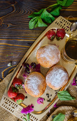 Background with delicious donuts, jam, tea, berries, and vibrant flowers. Summer food still life concept.