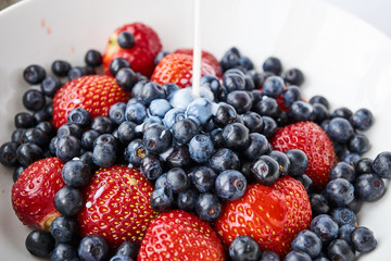 Strawberries, blueberries and milk in a white bowl