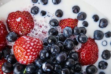 Strawberries, blueberries and milk in a white bowl