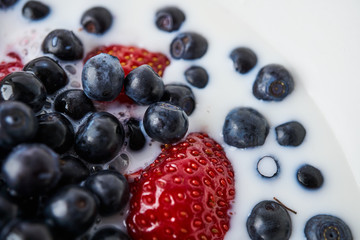 Strawberries, blueberries and milk in a white bowl