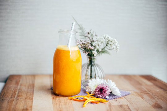 Healthy refreshing orange juice freshly squized from organic oranges and fruits, stands on wooden board in artisan and authentic hipster setting