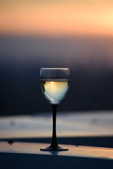 A glass with a white wine in the light of the setting sun. Vibrant alcohol background.