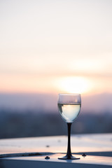 A glass with a white wine in the light of the setting sun. Vibrant alcohol background.