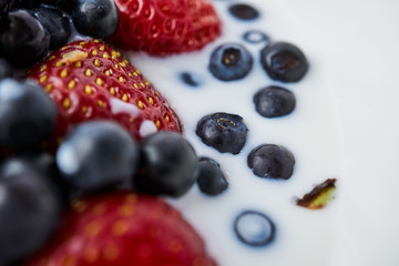Strawberries, blueberries and milk in a white bowl