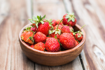 wooden bowl full of fresh strawberries on thewooden background