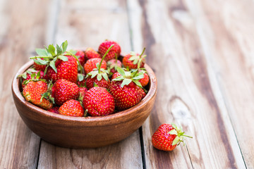 wooden bowl full of fresh strawberries on thewooden background