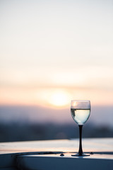 A glass with a white wine in the light of the setting sun. Vibrant alcohol background.
