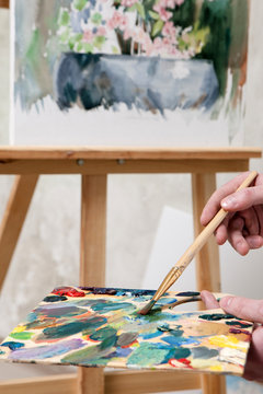 Artist paints a masterpiece. Palette of paint swatches with unfinished still-life painting on easel