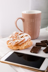 Sweets and cup of coffee closeup. Mobile phone on wooden table, morning breakfast concept
