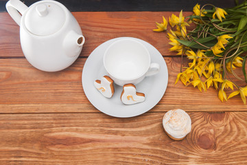 Teapot and cup with tulips on table. Cupcakes top view, breakfast background. Beautiful morning, tea party, celebration concept
