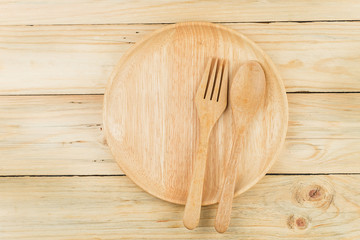 Wooden plate, wooden fork and wooden spoon on wooden talbe