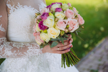 Closeup of bride hands holding beautiful wedding bouquet with white and pink roses. Concept of floristics