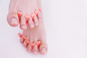 Woman's feet with ideal pedicure on white backdrop. Step for applying gel polish. Beauty spa procedure in salon, closeup background