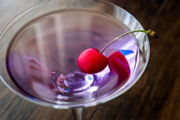 Blue Moon Cocktail with cherry on wooden surface.