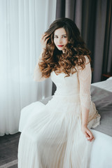 Fototapeta premium Luxury stylish bride sitting on the bed and looking at the camera