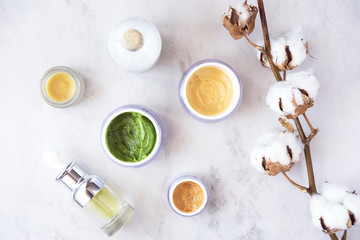Natural skincare cosmetic products on white marble table from above. Creams, balms, masks, oils, serums.   Beauty blogger concept