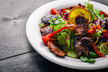 Salad with fresh cucumbers, tomatoes and greens with grilled meat on a plate Wooden board. Top view. Free space.