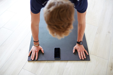 Ragazzo fitness a casa smartphone pettorali