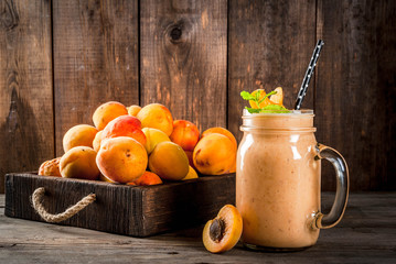 Homemade organic smoothie from yogurt and apricot. In Mason Jar, on a rustic old wooden table, with apricots and mint leaves. Copy space
