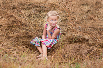 Naklejka na ściany i meble happy child girl in country style in hat relaxing on summer field with hay stacks