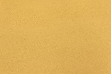 Yellow ochre painted stucco wall. Background texture