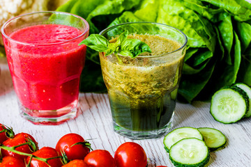 Fresh tomato juice and green detox smoothie in two glasses on a white wooden background. Close-up.