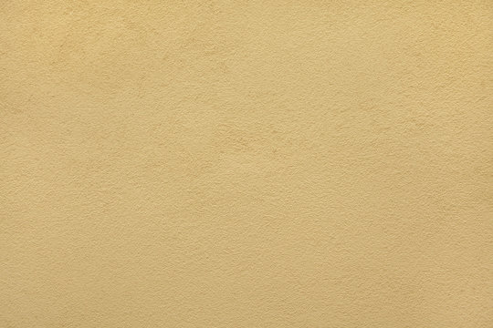 Yellow ochre painted stucco wall. Background texture