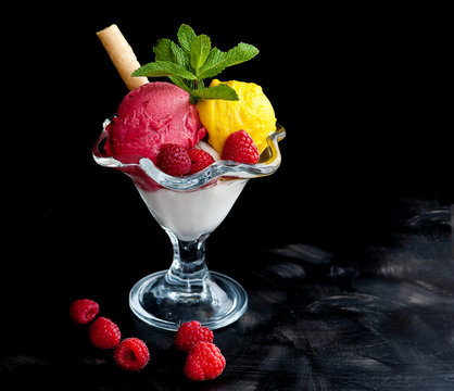 Ice cream in a glass cube with raspberries and mango