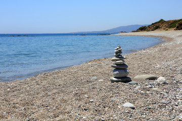 Stos płaskich kamieni na kamienistej plaży, Rodos, Grecja.