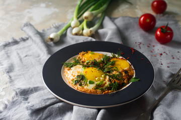 Fried eggs on the plate with cherry tomatoes,  spices and green onions in rustic style. Healthy breakfast, selective focus