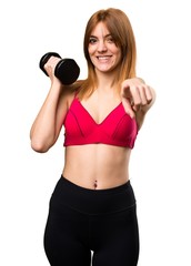 Beautiful sport woman with dumbbells pointing to the front