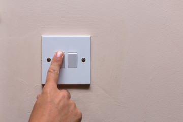 Finger turning off the light to save on consumption and energy
