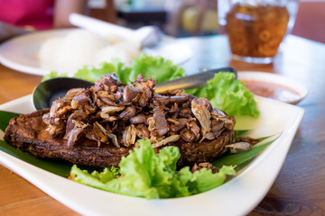 Thai food cuisine - Fried fish topped with garlic served on white dish with Thai spicy seafood sauce