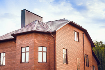 A large country house made of red brick with a tiled roof. The concept of the design of a modern country house.